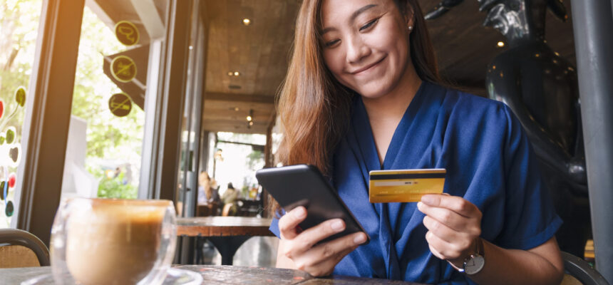 Closeup image of asian woman using credit card for purchasing and shopping online on mobile phone